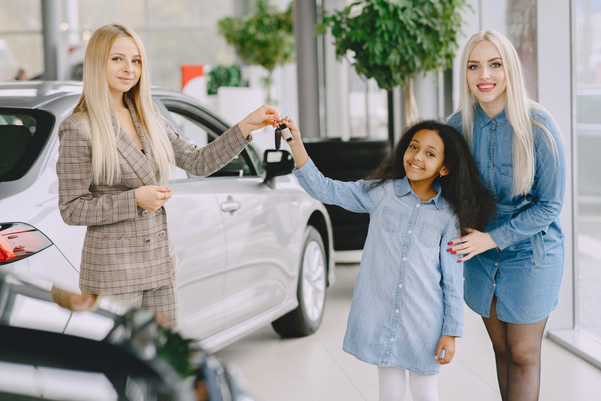 Family in a car salon. Woman buying the car. Little african girl with mther. Manager with clients.